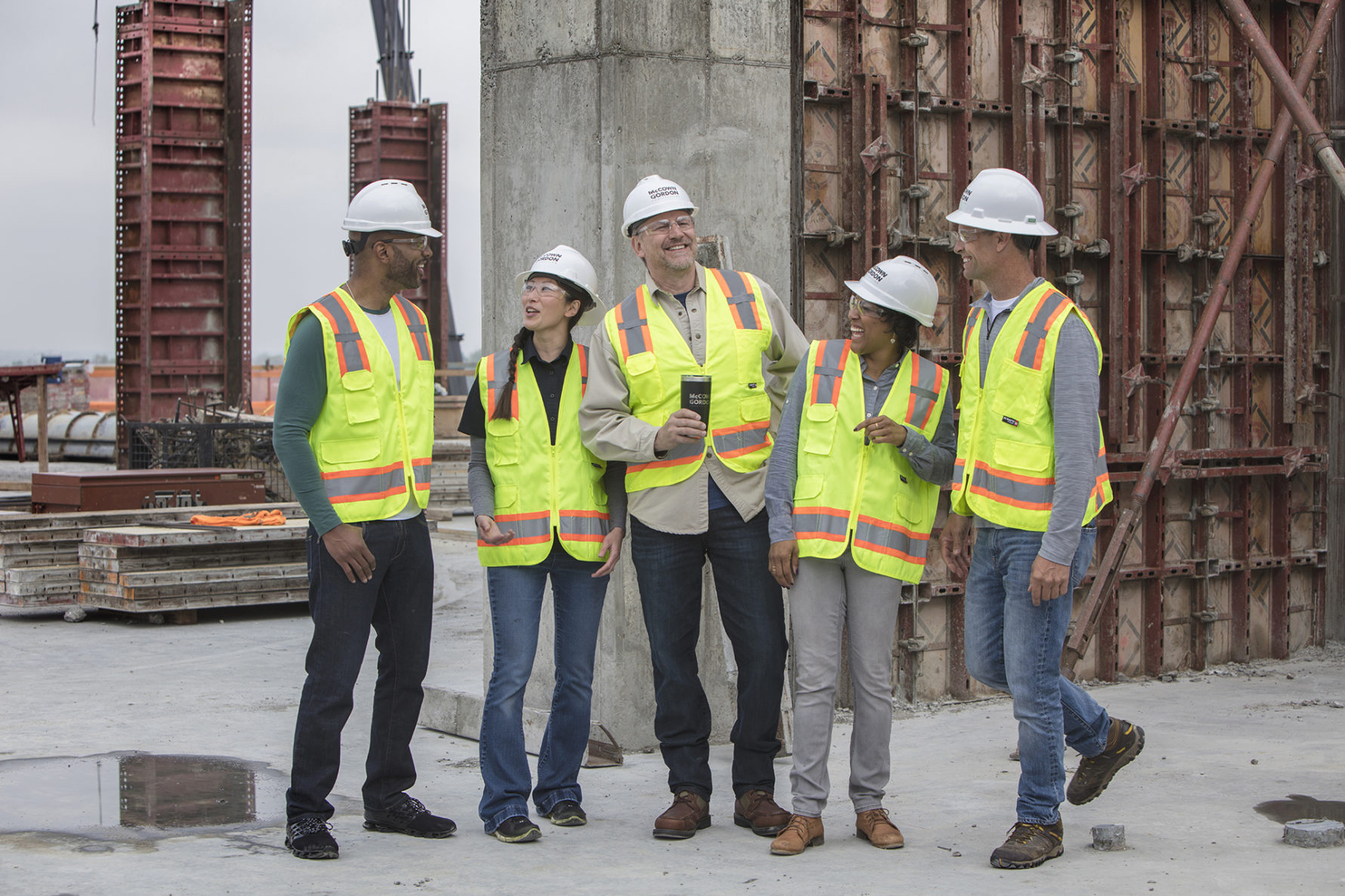 five McCownGordon employees with hardhats on the job site laughing