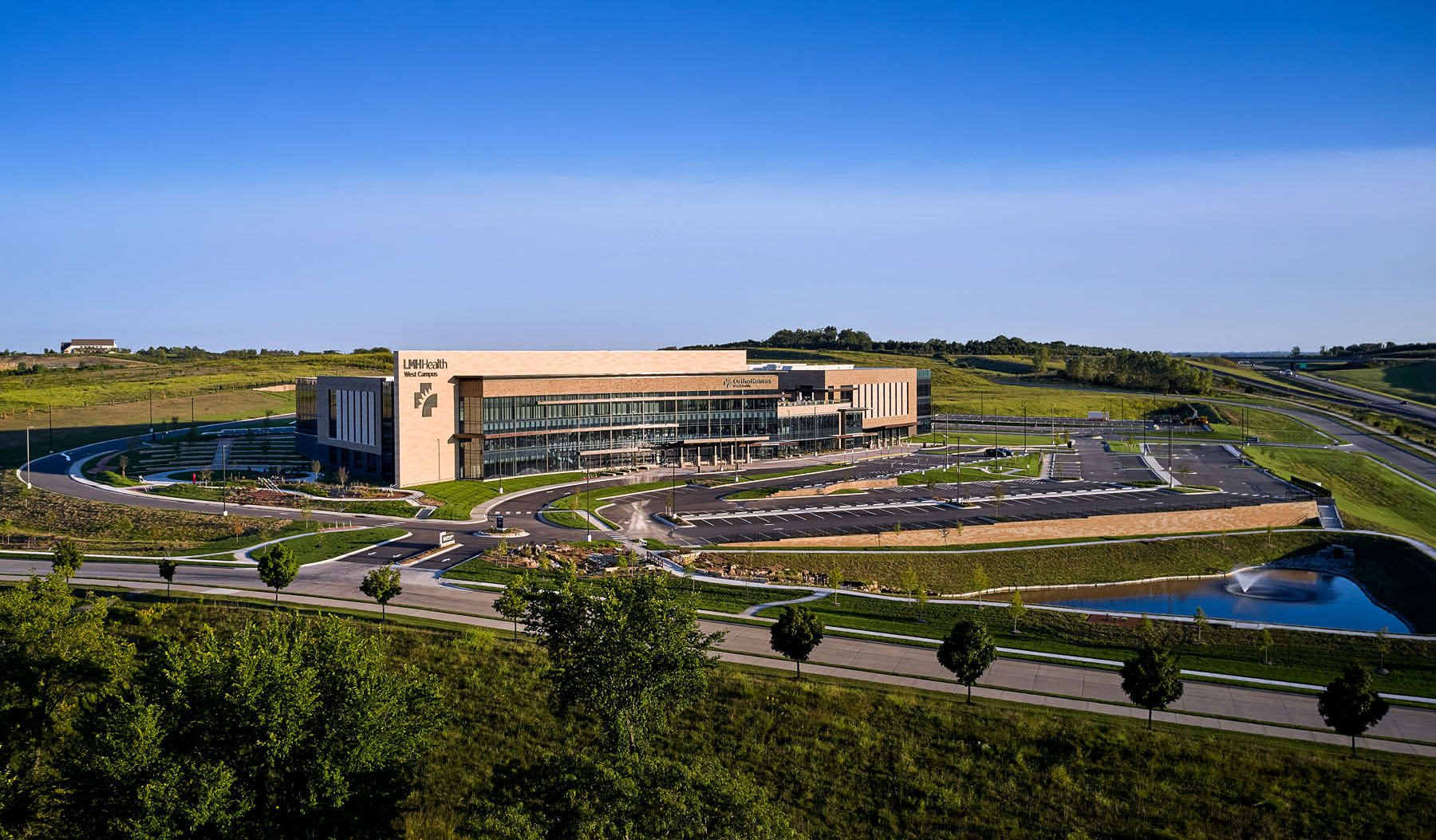 Aerial view of LMH Health West in Lawrence, KS. Includes a pond and walking trail