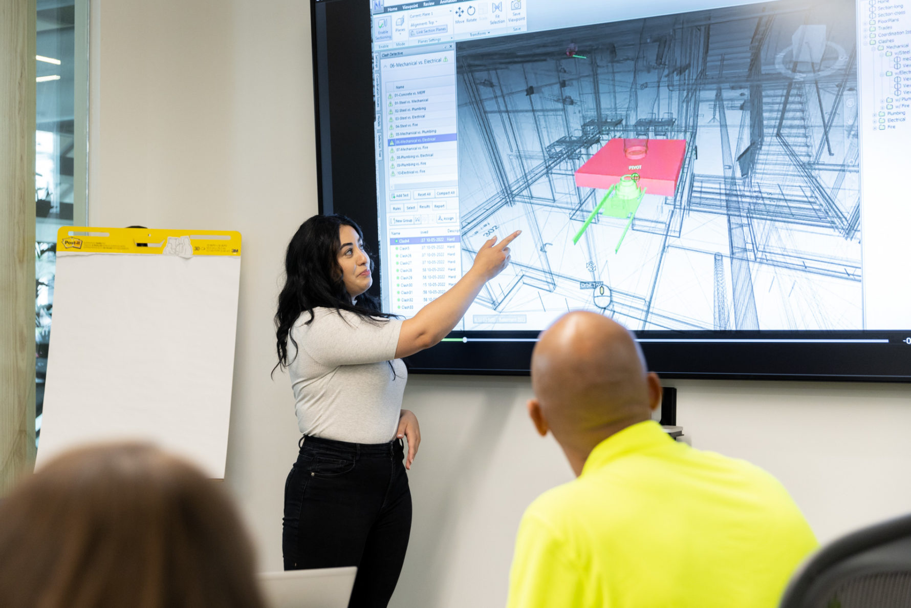 A McCownGordon Construction associate pointing at plans on a screen during a meeting in the office
