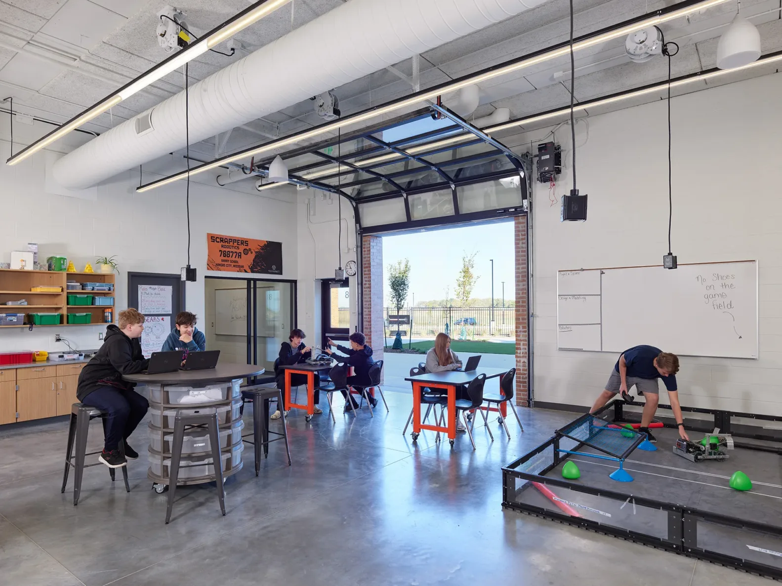 students working in the robotics classroom at Platte Purchase Middle School with the glass garage door open to the outdoors.