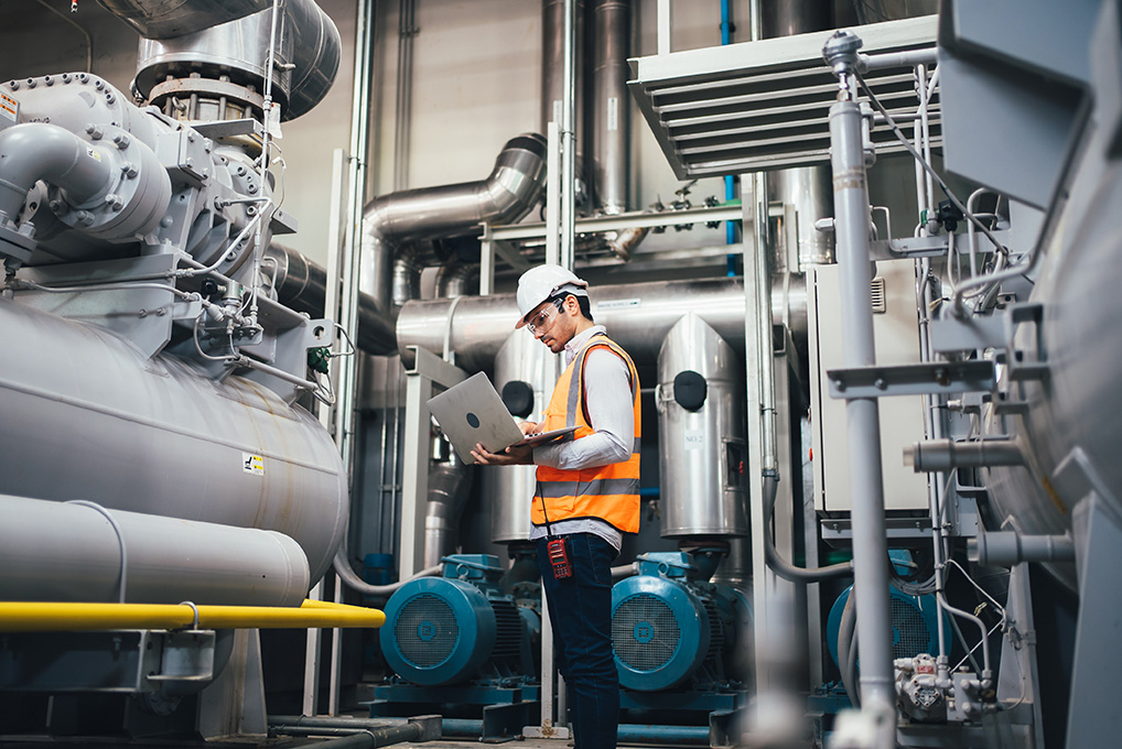 Man working in a manufacturing facility using his laptop