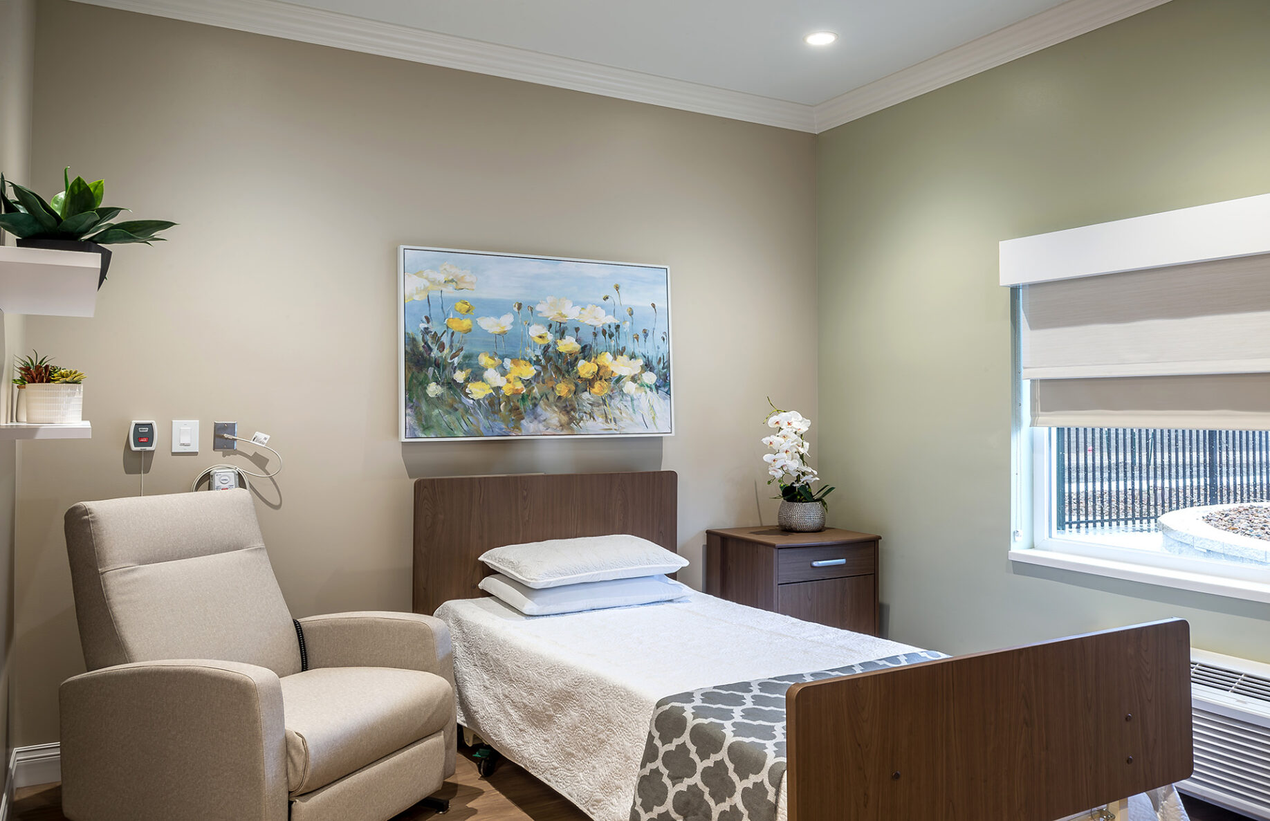 Senior living room with a bed and chair that overlooks the outdoor area at Logan Intergenerational Family Education Center.