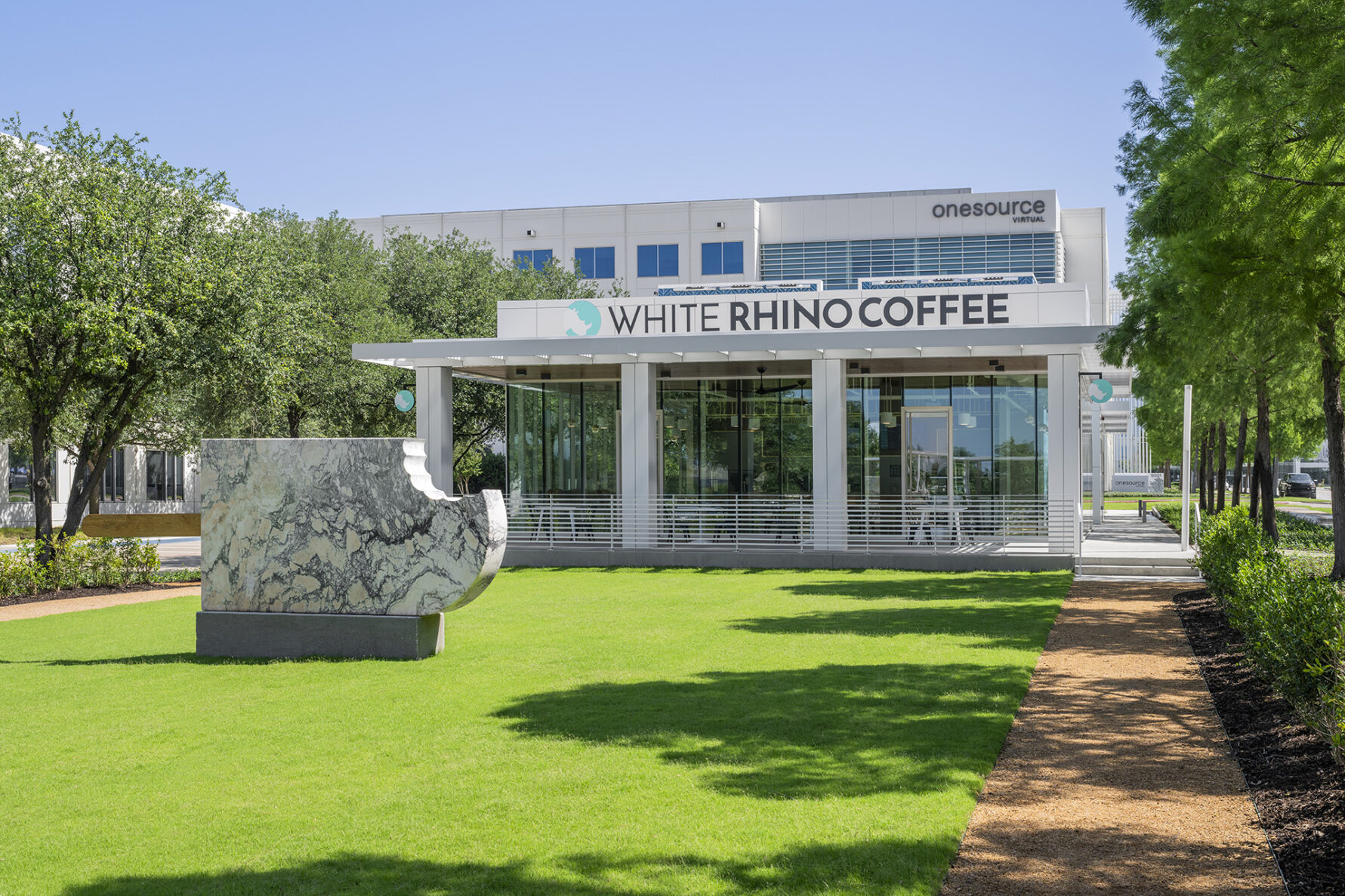 Exterior photo of White Rhino Coffee and green space in Dallas Texas